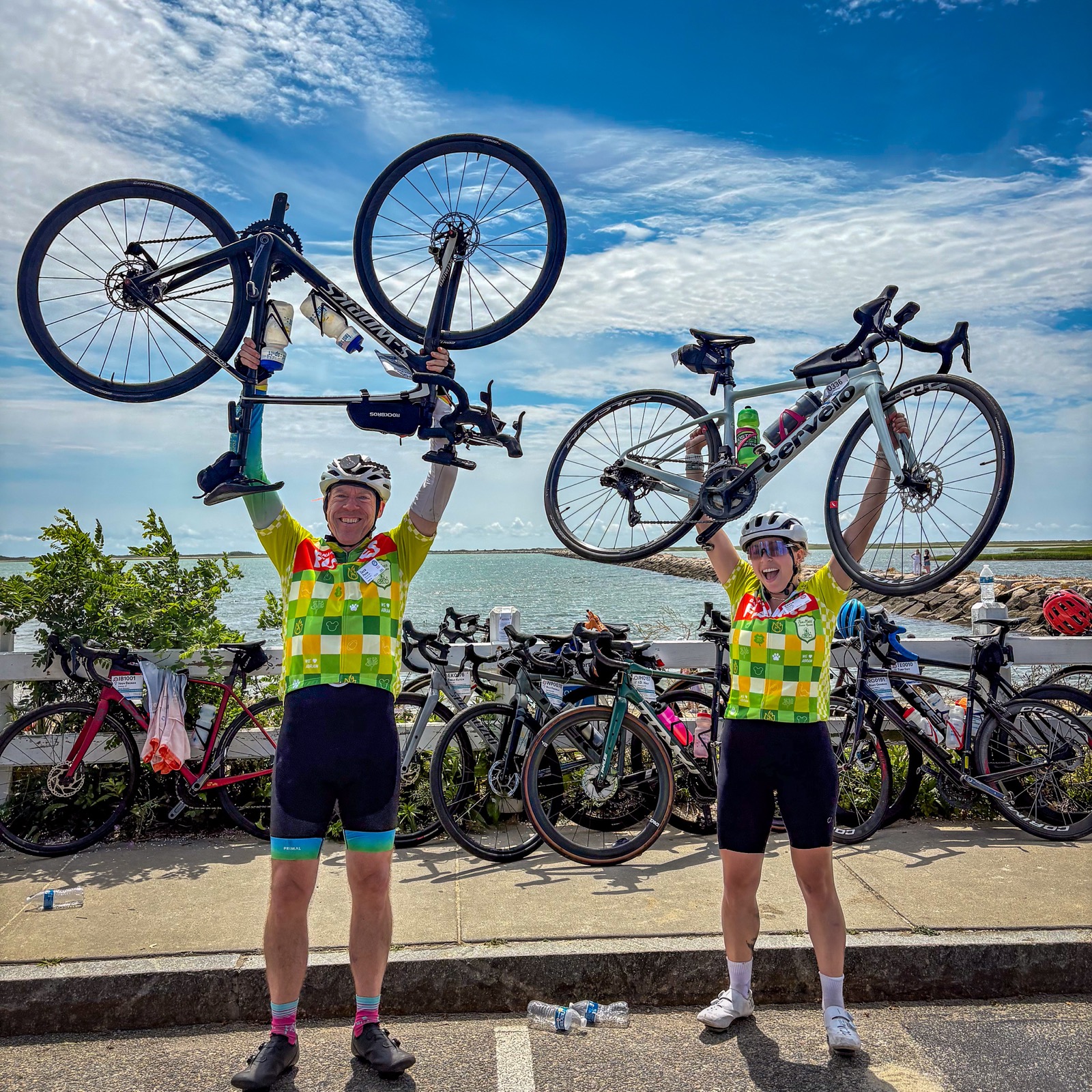 Bikes raised overhead at the finish by the water